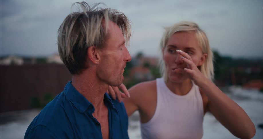 A man and a woman acting in a romantic manner while sharing a slice of pizza