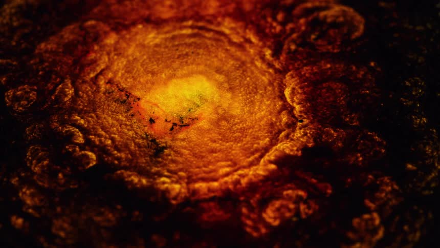 A close up of a bright orange liquid retracting surrounded by a dark cloud