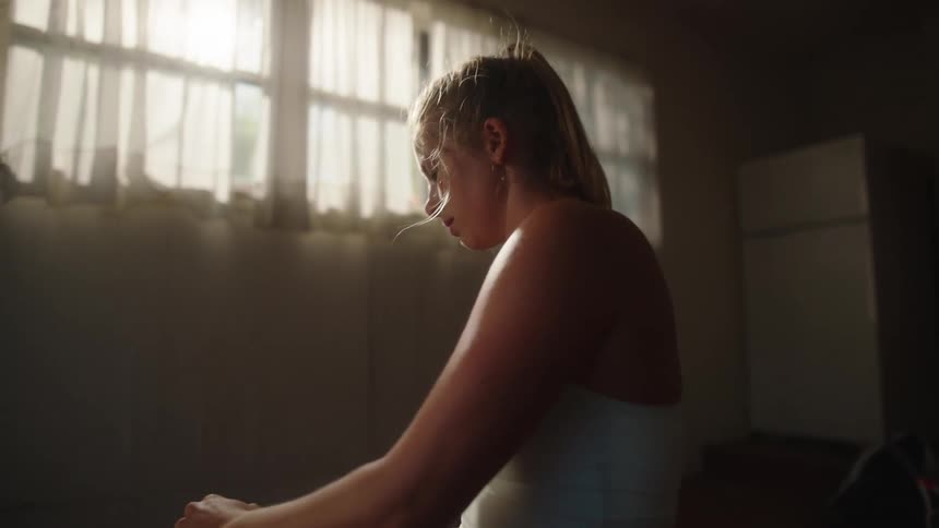 Woman stretches on the floor of a dimly lit room