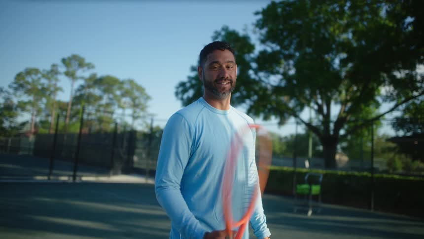 Bearded man spinning a racket on a tennis court