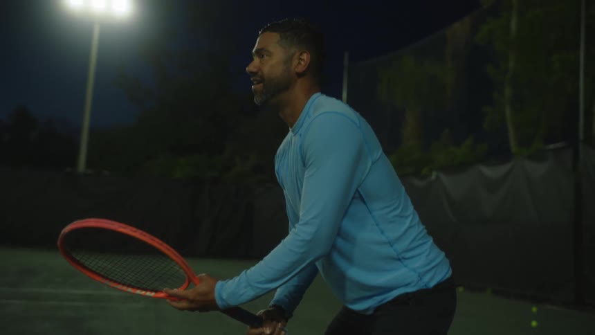 A male tennis player spins his racket while on court