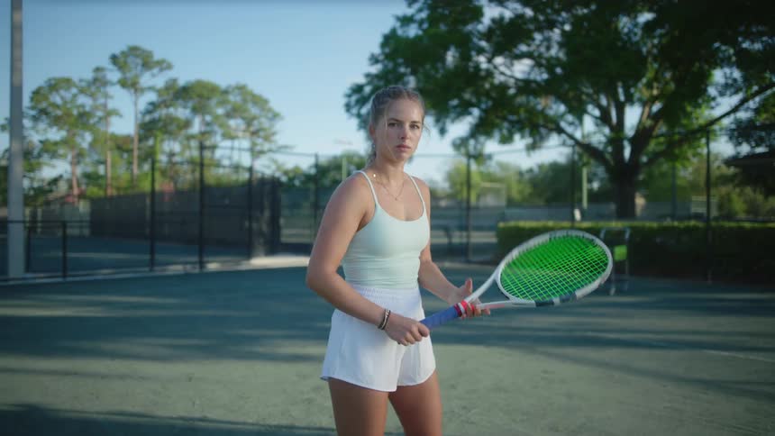 Young blonde woman on a tennis court swinging a racket
