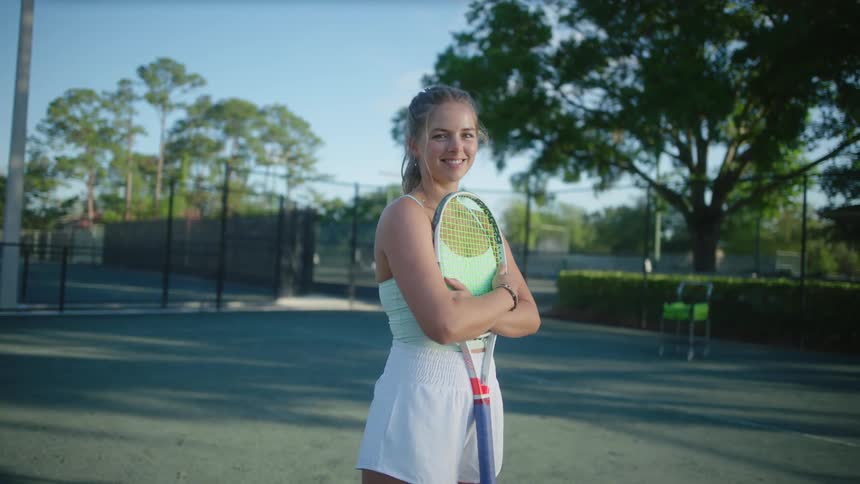 Woman on a court holding a racket and smiling
