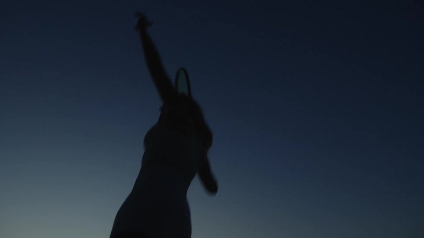 Silhouette of a woman with a racket playing tennis in the late afternoon
