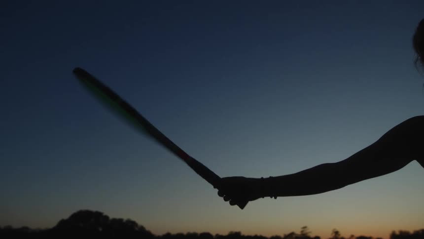 Silhouette of a womans arm holding a tennis racket