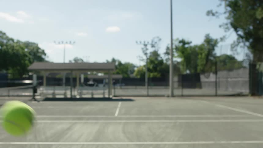 Hand holding a racket hits a tennis ball