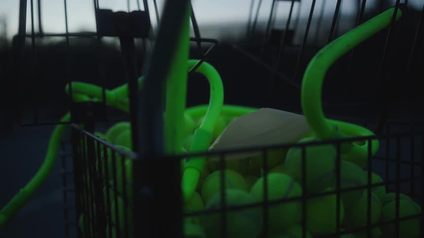 Black wire basket filled with neon green tennis balls