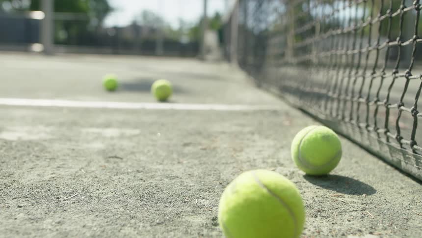 Tennis ball rolls across the ground on tennis court near the net