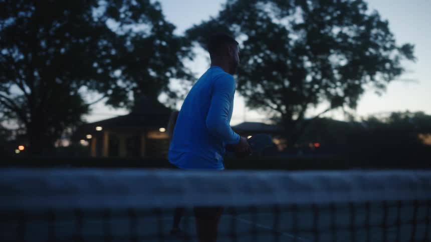 Man and woman on a tennis court stretching their legs