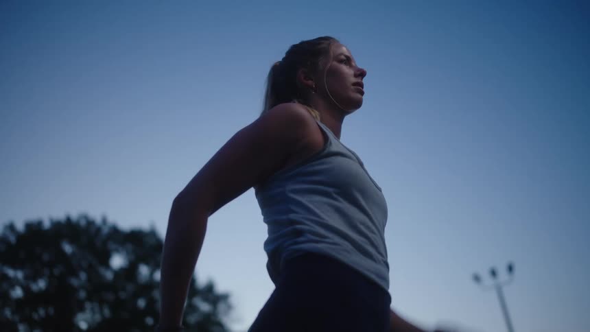A young woman outdoors wipes sweat off of her face