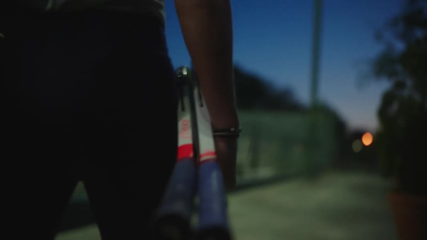 Closeup of a woman walking at night with two rackets in her hand
