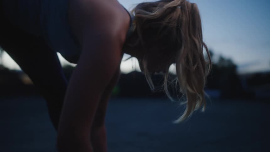 A lady stretching on the court in the morning