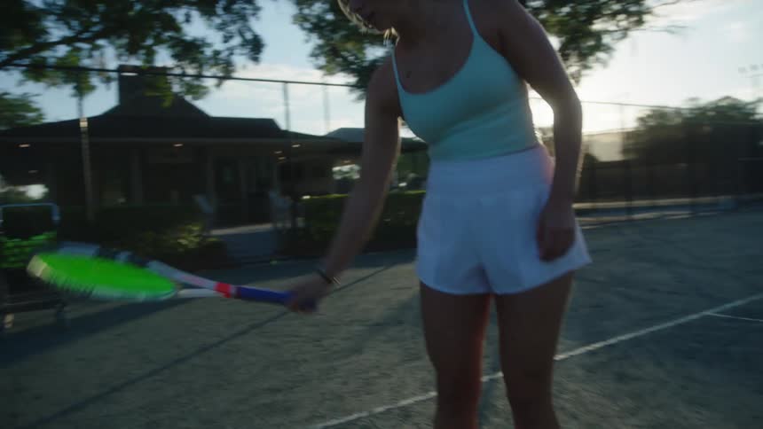 Woman catching tennis ball with racket on a court