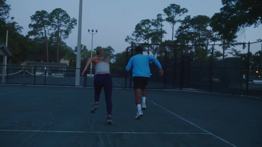 A couple doing warm ups on a tennis court at morning practice