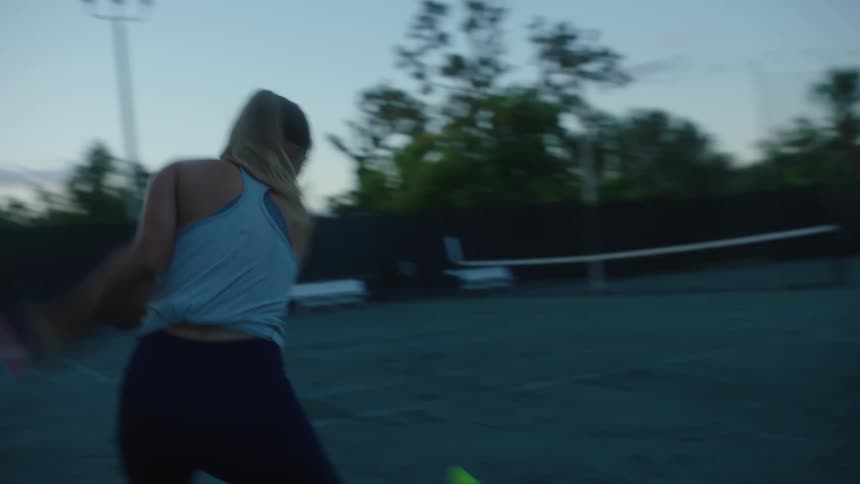 Woman playing tennis on a court and in a sunrise
