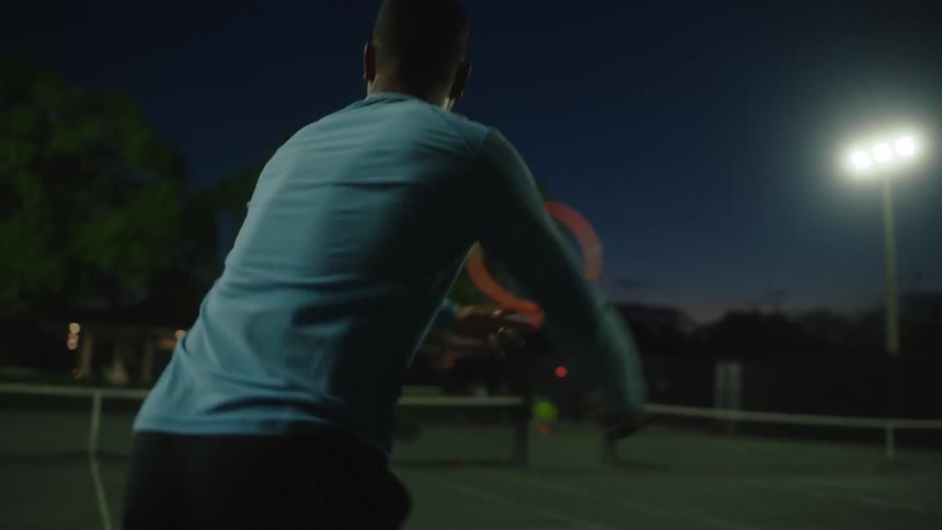 A male tennis player volleying with another player