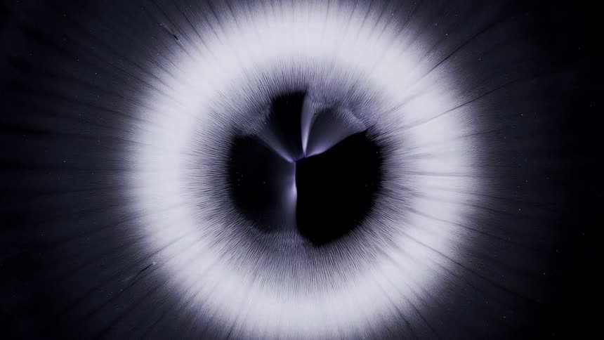 Extreme closeup on a dense glowing liquid expanding on a black background