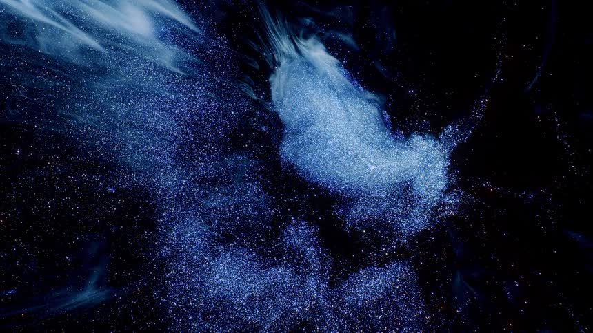 Dense liquid exploding exhausting shine against a black background