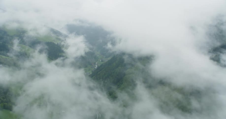 Aerial panorama of clouds passing over green mountains