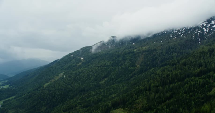 Low lying clouds float over forested mountain near a rural town