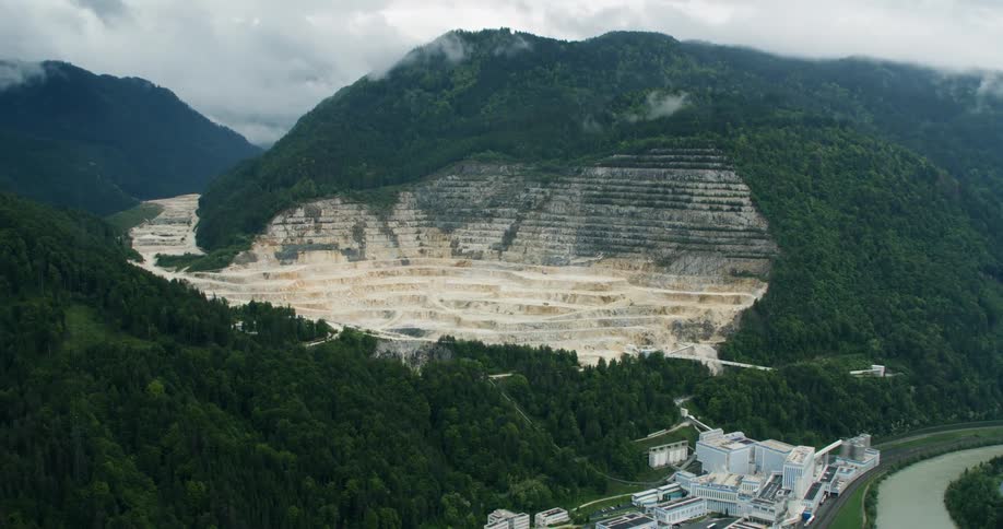 Aerial panorama of a mountain worn by stone removal and a greenish forest around it