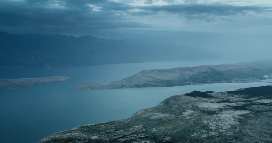 Aerial panorama of mountains and hills at the edge of an ocean on a cloudy day