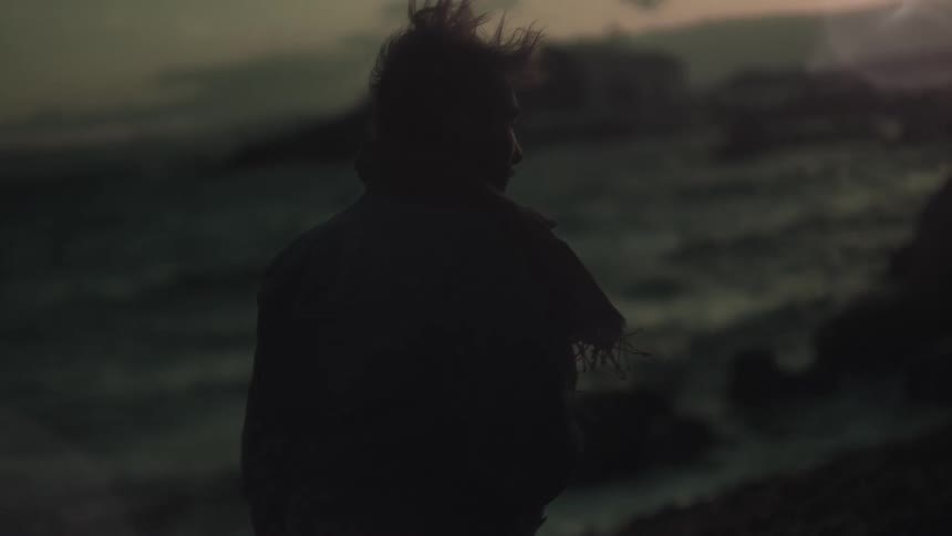 A man walks by the beach at sunset