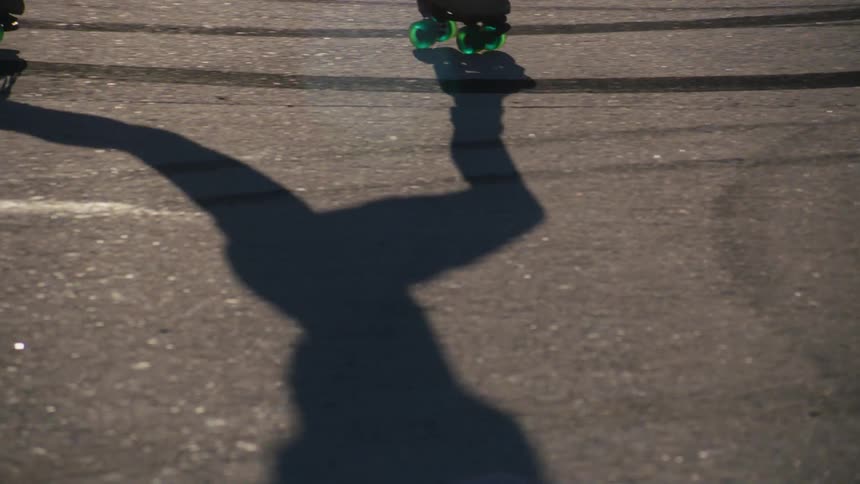 Shadow of a woman skating on an asphalt surface