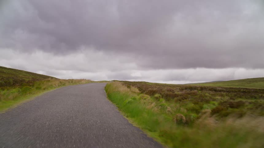 A country lane and cuts through fields of grass