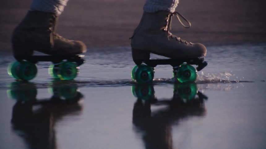 A person is roller skating through a puddle