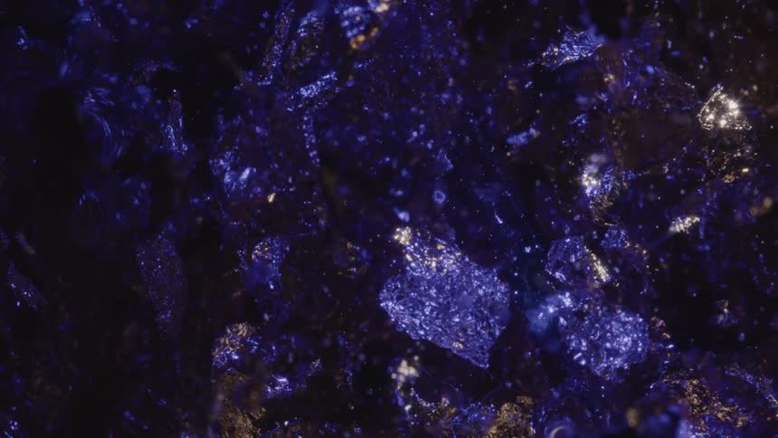An animation of several space rocks floating in space and there is a blue color hitting them