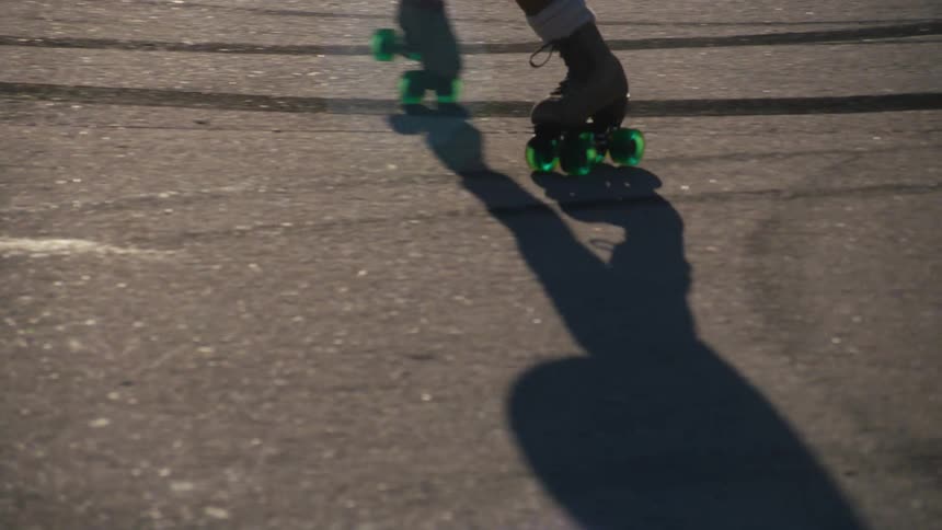 A person using a roller with green wheels going backwards on a concrete floor