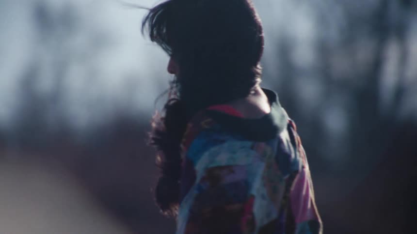 Back of a woman with long hair wearing a colorful sweater skating on a windy day