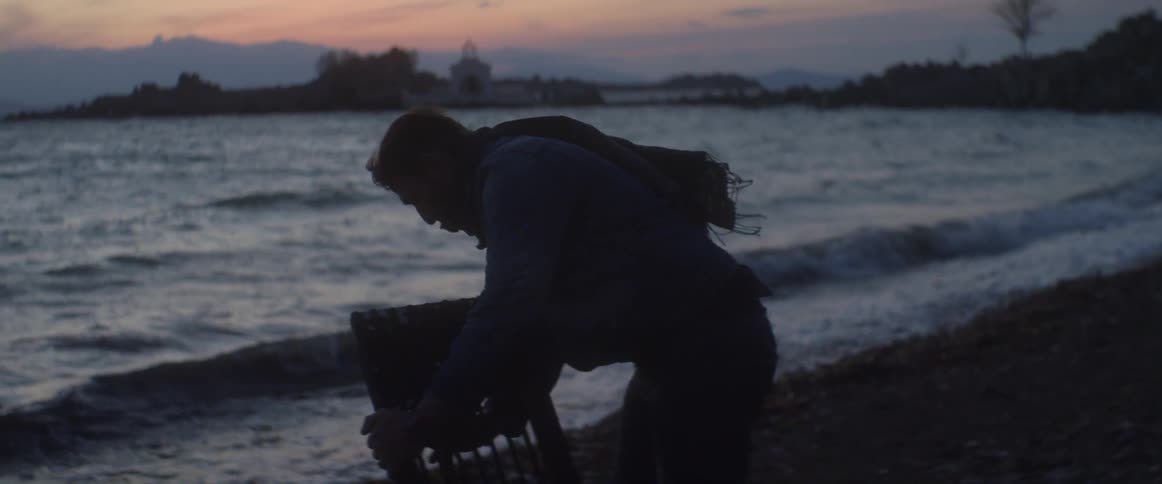 A man sets up a board on a beach at dusk