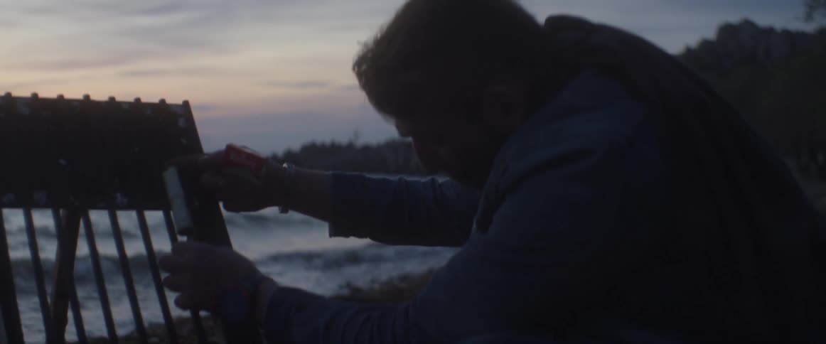 A man examines a firework on the beach