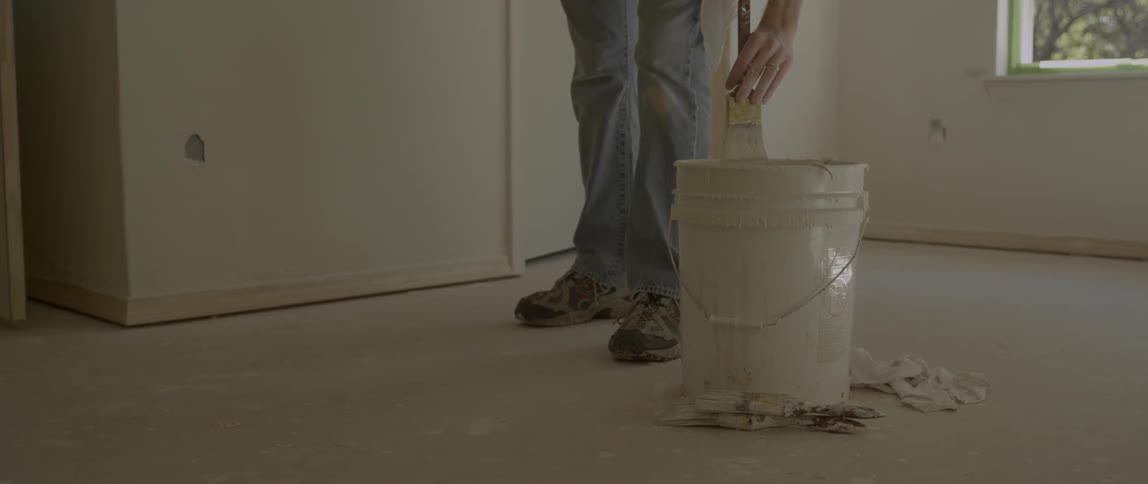 Homeowner dipping brush into a paint bucket