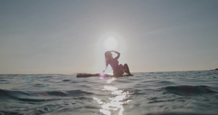 A woman sitting on a raft in a sea with small waves and strong sunlight