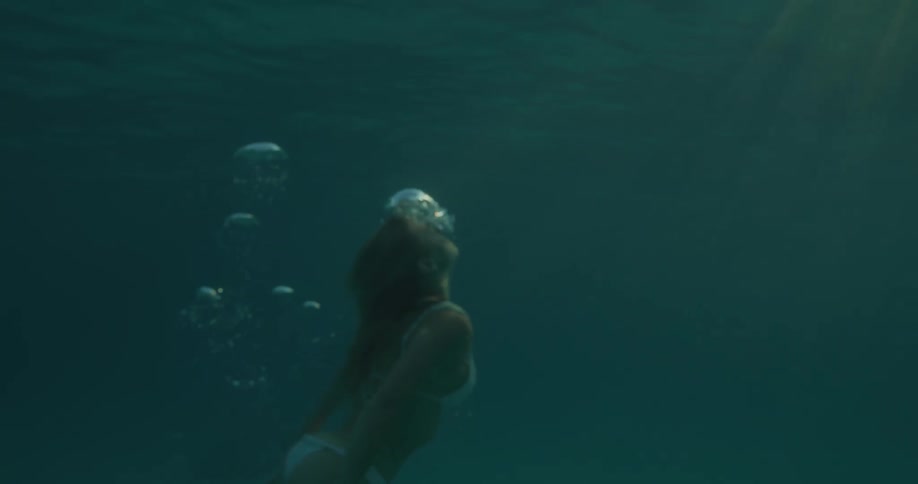 Woman submerged in the ocean rising towards the surface