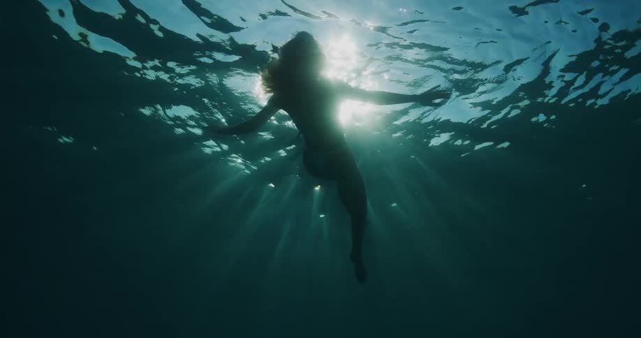 A woman swimming underwater floating near the surface