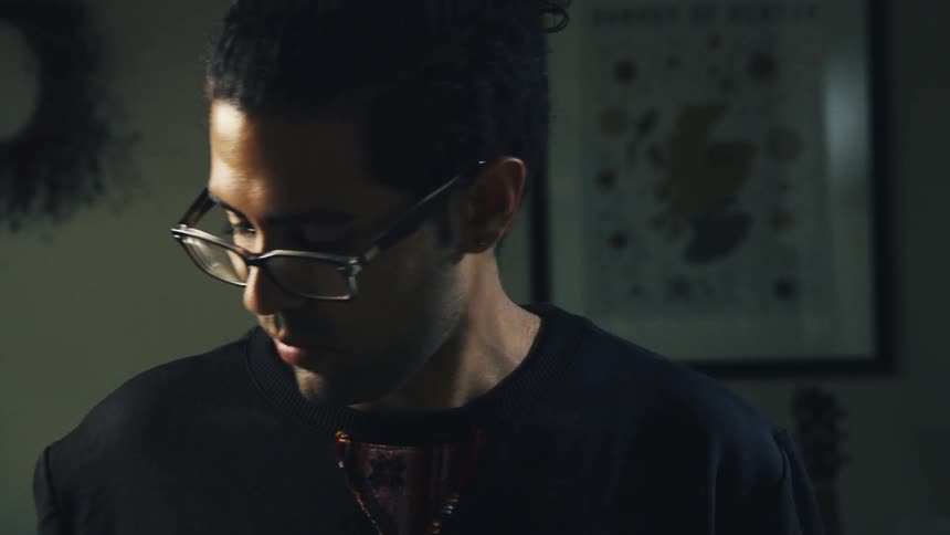 A man with dark hair and glasses cooking in a dimly lit room at home