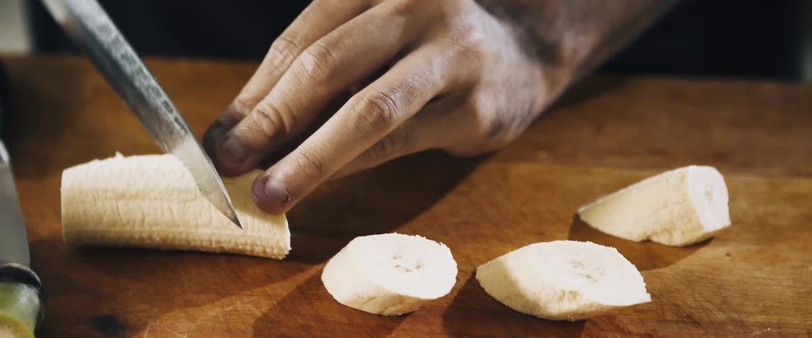 A man is cutting up a banana