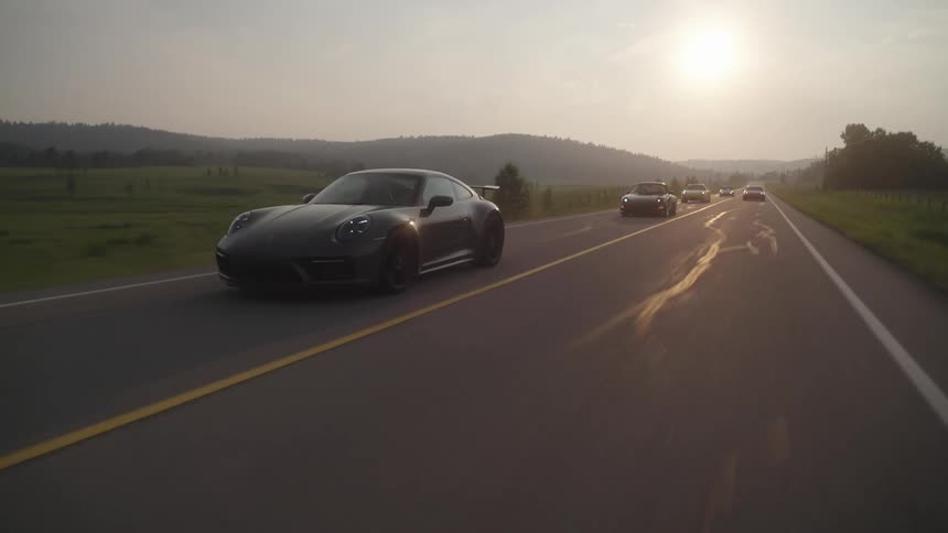 Several sports cars traveling on a long highway