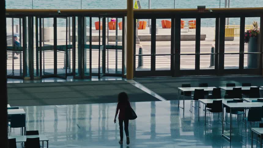 A woman walks through the lobby of the building towards the exit