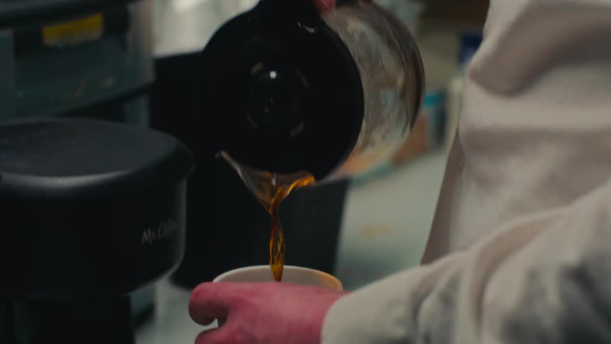 Hands of a person taking a disposable plastic cup and preparing a coffee