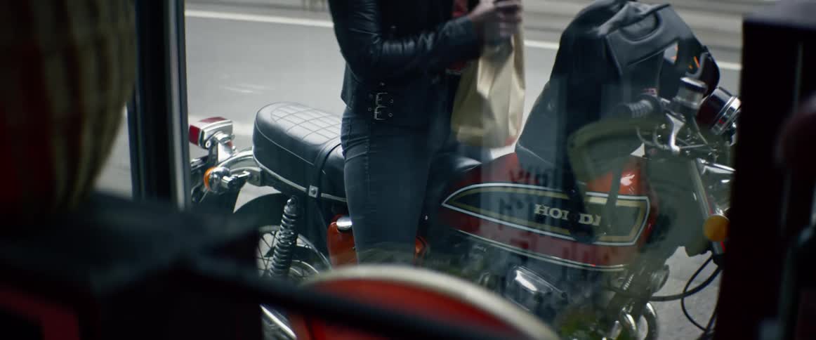 A woman puts a bag in her backpack and gets on her motorcycle