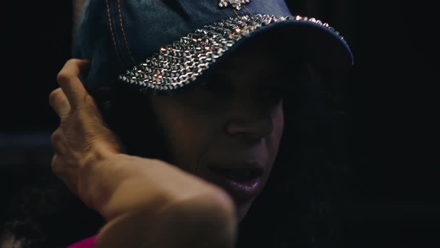 A woman putting a cap with shiny details on her head and she is talking