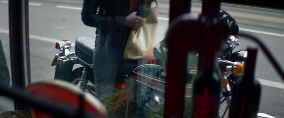 A woman finishes shopping and gets on her motorcycle