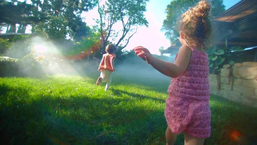Two children running in a garden