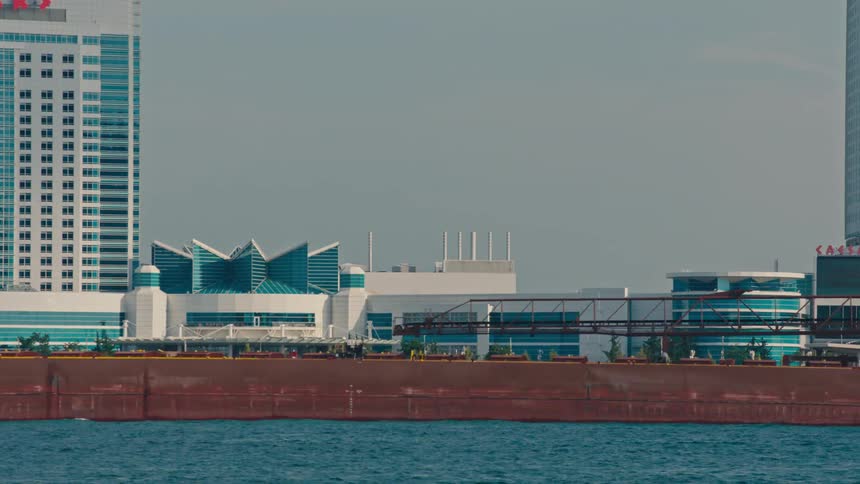 A large freight ship passes by the city