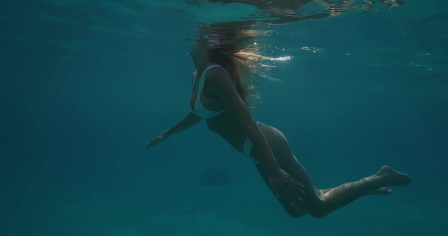 Woman with brown hair and bikini swimming in the ocean